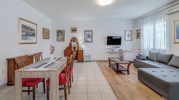 Un salon comprenant un coin repas, un canapé, un téléviseur et des œuvres d’art accrochées aux murs.