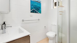 A bathroom with a white sink, a toilet, and a glass shower enclosure. - Kiama Coastal Escape (Kiama)