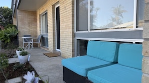 A balcony with a blue cushioned seating area, a small table, and chairs. - Kiama Coastal Escape (Kiama)