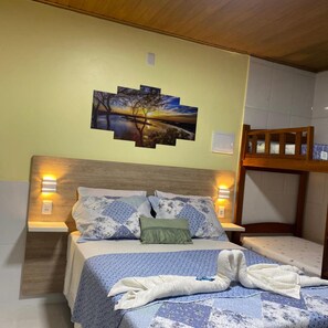 A bed with a headboard, pillows, a blanket, and a towel. There is a wall-mounted picture above the bed. - Chalé Mobilado em Condomínio Porto dos Lençóis Lençóis Maranhenses (Barreirinhas)