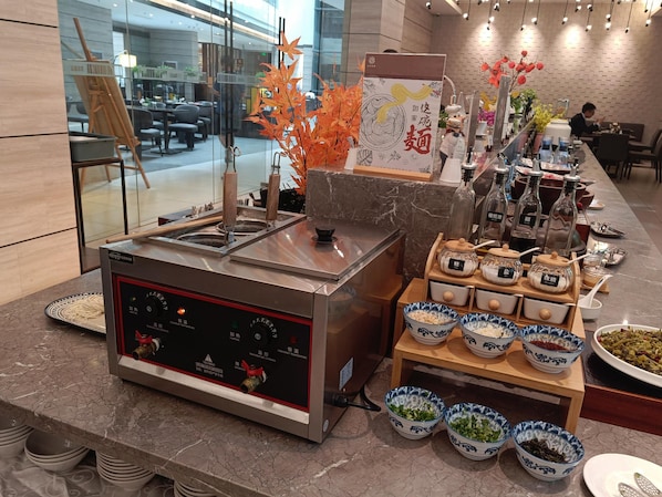 A buffet setup with a temperature control machine, various food containers, and decorative elements like autumn leaves. - Homeinn Plus (Suzhou)