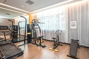 A modern gym with exercise equipment, a treadmill, and a stationary bike. - Echarm Hotel (Zhuhai)