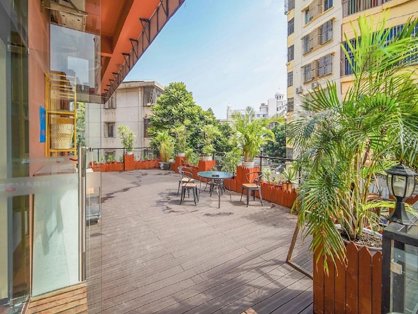 Una terraza en la azotea con suelo de madera, mobiliario exterior y plantas en macetas.