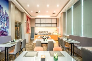 A hotel dining area with tables, chairs, and a buffet setup. - Echarm Hotel (Zhuhai)