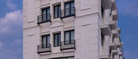A multi-story hotel with a white facade, balconies, and a sign with the name 'ESSENIA'.