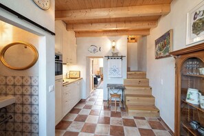 A kitchen with white cabinets, a wooden staircase, and a dining area with a table and chairs. - Charming house with patio near Lake Lugano (Magliaso)
