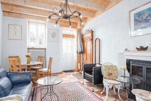 A cozy living room with a fireplace, a dining area with chairs and a table, and a sofa. - Charming house with patio near Lake Lugano (Magliaso)