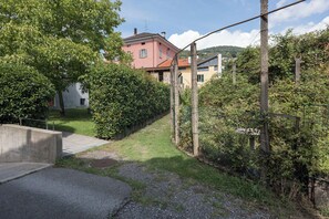 A residential area with a paved pathway leading to a house with a red roof. - Charming house with patio near Lake Lugano (Magliaso)