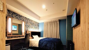 Quarto de hotel com cama, secretária com computador, cadeira, televisão e espelho.