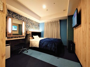 Una habitació d'hotel amb llit, escriptori amb ordinador, cadira, televisió i mirall.