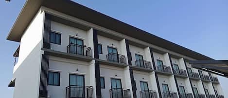A multi-story building with balconies, windows, and a flat roof.