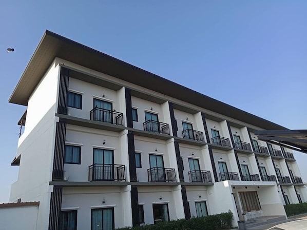 A multi-story building with balconies, windows, and a flat roof.