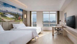 A hotel room with two beds, a desk, a TV, and a large window with a view. - Vienna International Hotel (Chongqing)
