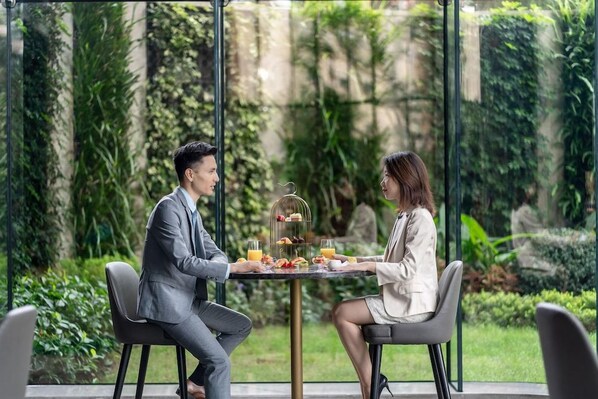 Two individuals seated at a table with a birdcage centerpiece, surrounded by greenery. - The G Shenzhen, A Tribute Portfolio Hotel (Shenzhen)