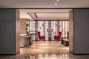 A modern reception area with a counter, two red chairs, and a bookshelf. - The G Shenzhen, A Tribute Portfolio Hotel (Shenzhen)