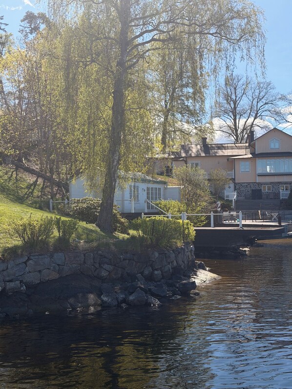 A waterfront property with a stone wall, a dock, and a house with a stone facade.