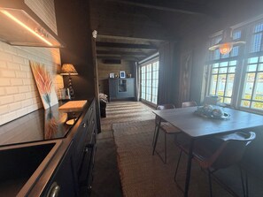 A modern kitchen with a dining area, large windows, and a view of the outdoors.