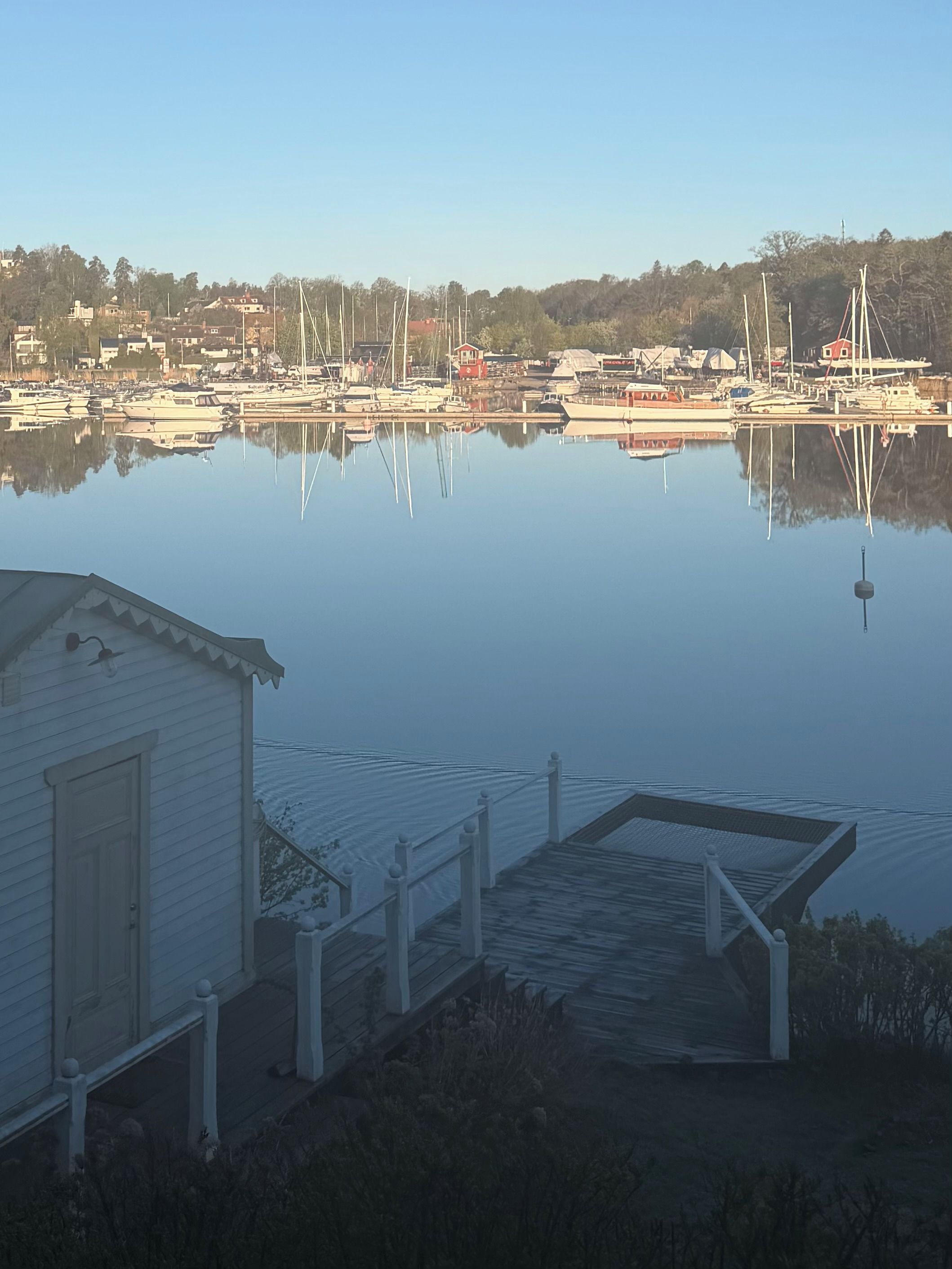 A marina with boats docked, a wooden dock, and a small building.