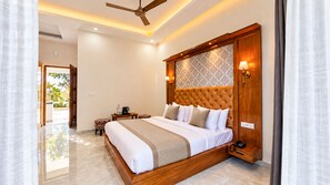 A hotel room with a large bed, a ceiling fan, a bedside table with a lamp, and a view of the outdoors. - Yellow Tail by Yesotel (Ramnagar)