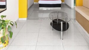 Una camera d'albergo moderna con un letto, un tavolino in vetro e una pianta in vaso.