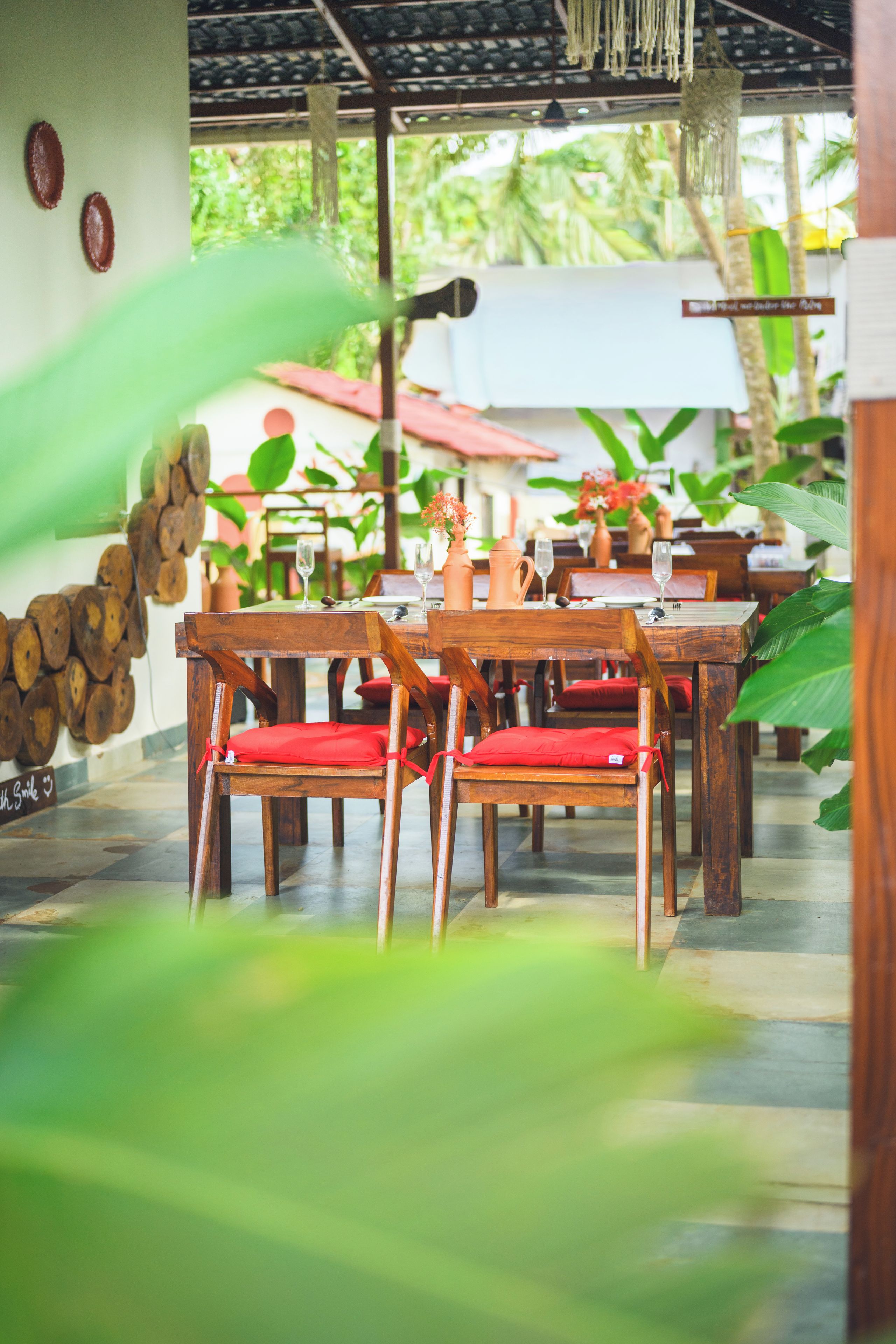 A restaurant with wooden tables and chairs, some with red cushions.