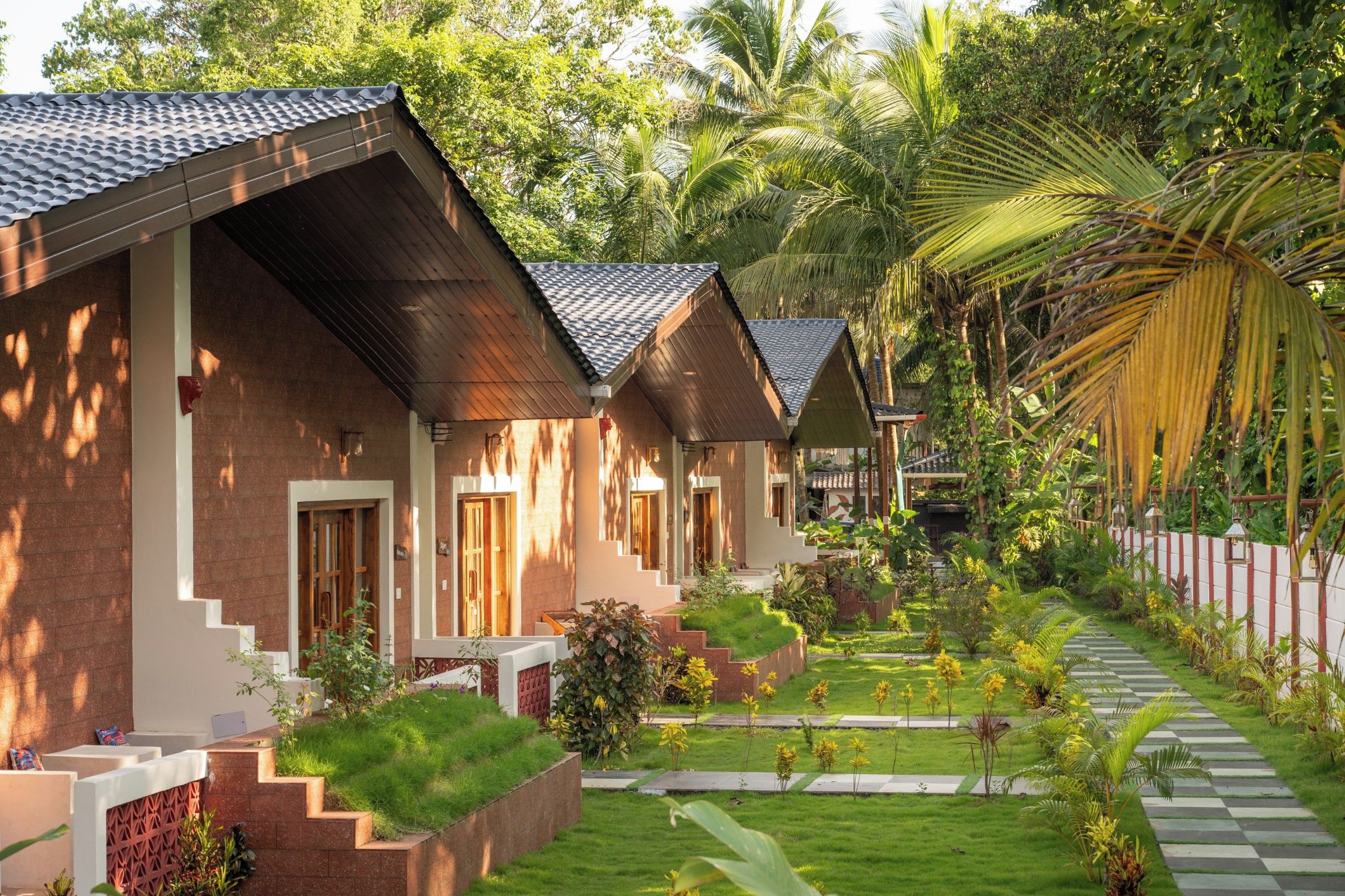 Eine Reihe von bungalows mit Gartenweg und tropischer Vegetation.