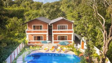 Un edificio de dos pisos con piscina y mobiliario exterior.