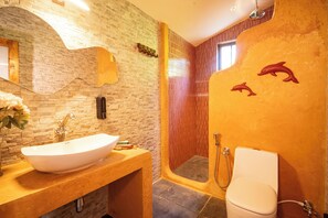 Une salle de bain avec un lavabo blanc, un miroir, une douche et des toilettes.