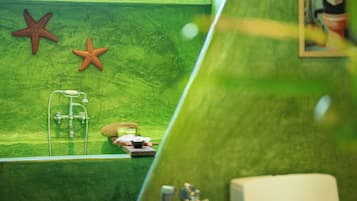 Ein Badezimmer mit grüner Wand, zwei Seestern-Dekorationen, einer Badewanne und einer Dusche.