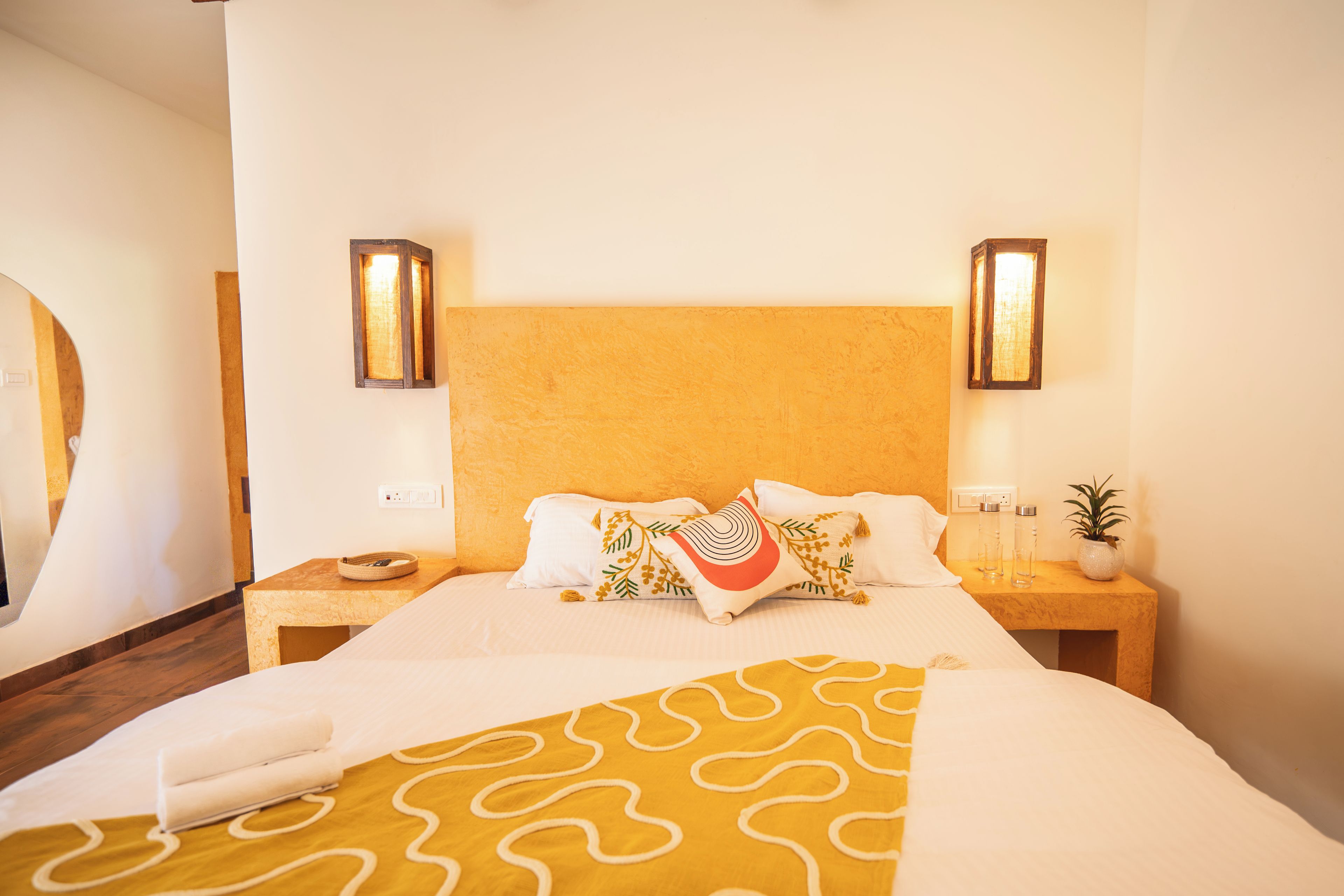 A hotel room with a large bed, two bedside tables, a headboard, and wall-mounted lighting.
