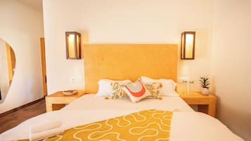 Habitación de hotel con una cama grande, dos mesitas de noche, un cabecero e iluminación empotrada.
