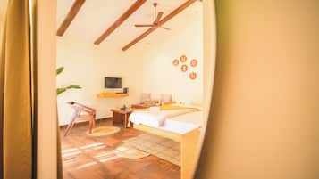 Una habitación con una cama, un escritorio, una silla, un televisor y un ventilador de techo.