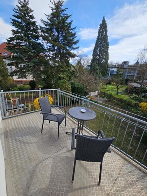A balcony with two wicker chairs and a small round table, surrounded by a metal railing. - At the Steigerwald (Erfurt)