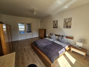 A bedroom with a wooden bed, a nightstand, a wardrobe, and a door with frosted glass panels. - At the Steigerwald (Erfurt)