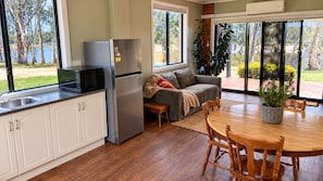 A kitchen with a refrigerator, microwave, and sink. There's a dining area with a table and chairs.