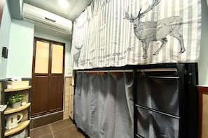A room with a striped curtain, a door, and a shelf with items. - Royal Paris Guesthouse (Kowloon)
