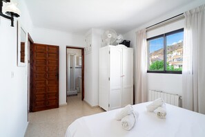 Ein Hotelzimmer mit einem Bett, einem Kleiderschrank, einer Dusche und Blick auf Gebäude.