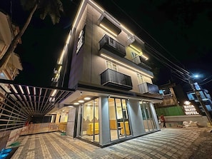 A modern hotel with a flat roof, large windows, and a well-lit entrance.