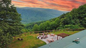 A rooftop terrace with outdoor seating and a view of a forested valley.