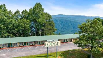 A motel with a green roof, a sign reading 'Saluda Mountain Lodge,' and a parking lot in front.