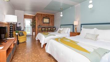 A hotel room with two beds, a desk, a sofa, and a kitchenette.
