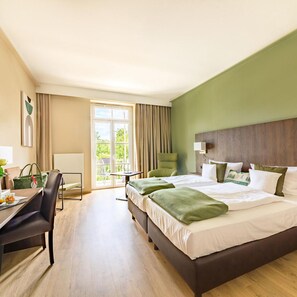 Quarto de hotel com uma cama grande, uma escrivaninha, uma cadeira e vista para o exterior.