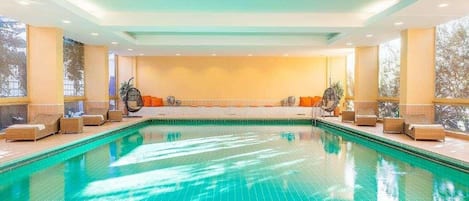 Una piscina interior con varias zonas de descanso y asientos.