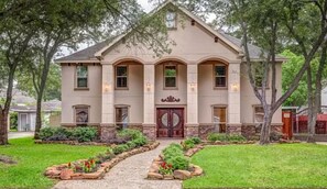 A two-story house with a symmetrical facade, a central entrance with a double door, and a well-maintained front yard with a gravel path leading to the door. - Experience resort style luxury at the stylish Houston property with a private pool. Minutes from the city's top dining and shopping. (Houston)