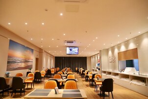 A conference room with rows of tables and chairs, a large screen at the front, and a mural on the wall.