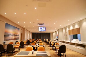 A conference room with rows of tables and chairs, a large screen at the front, and a mural on the wall. - Ausotel by Argyle Qinzhou (Qinzhou)