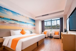 Habitación de hotel con una cama grande, un escritorio, una silla y vistas a la ciudad a través de amplios ventanales.