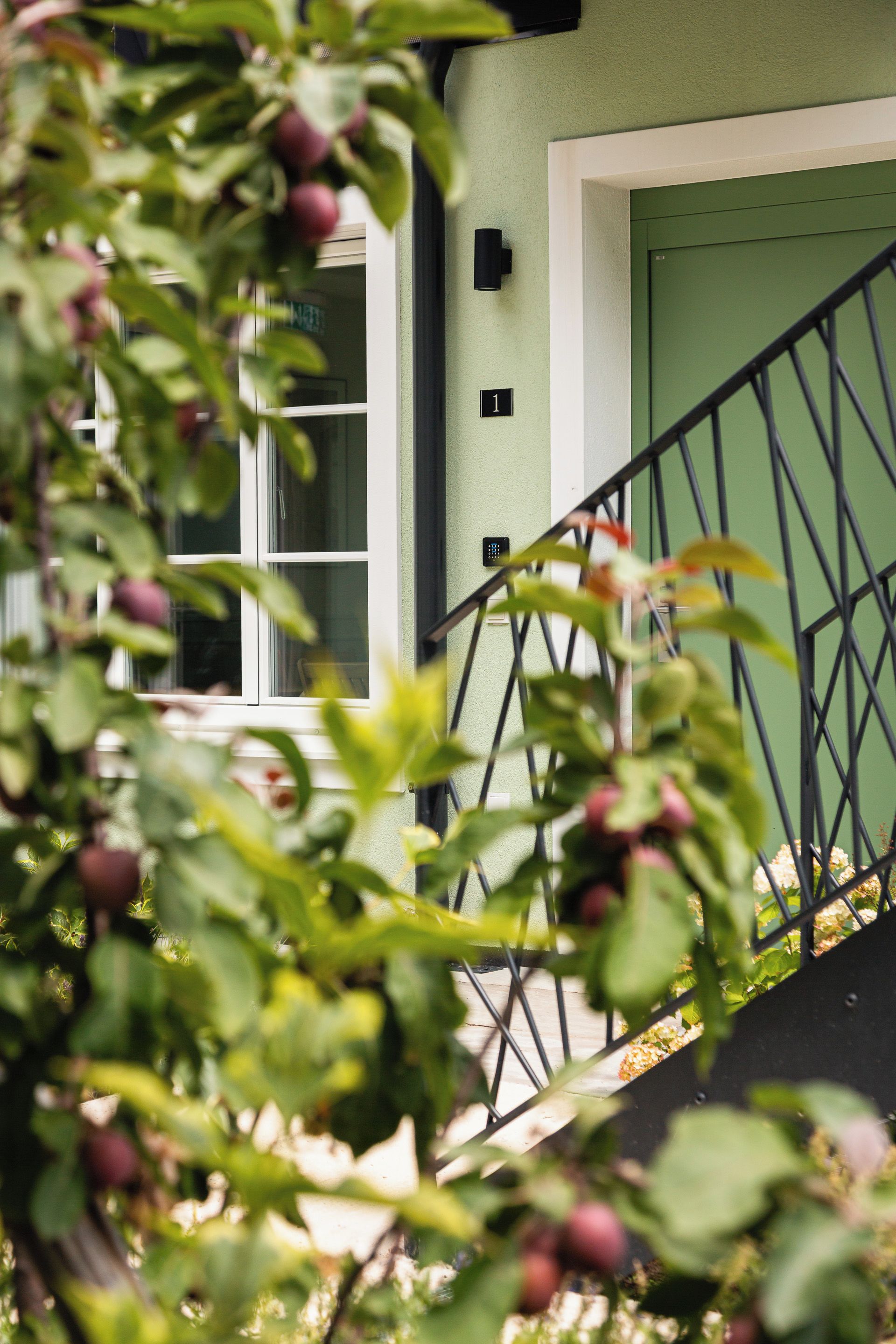 A building with a green door, a white window, and a black security keypad.