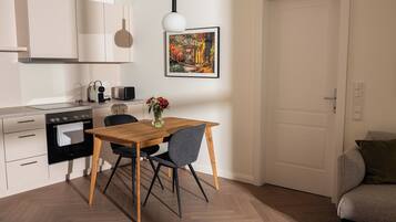 A modern kitchen with a dining table, chairs, and a painting on the wall.