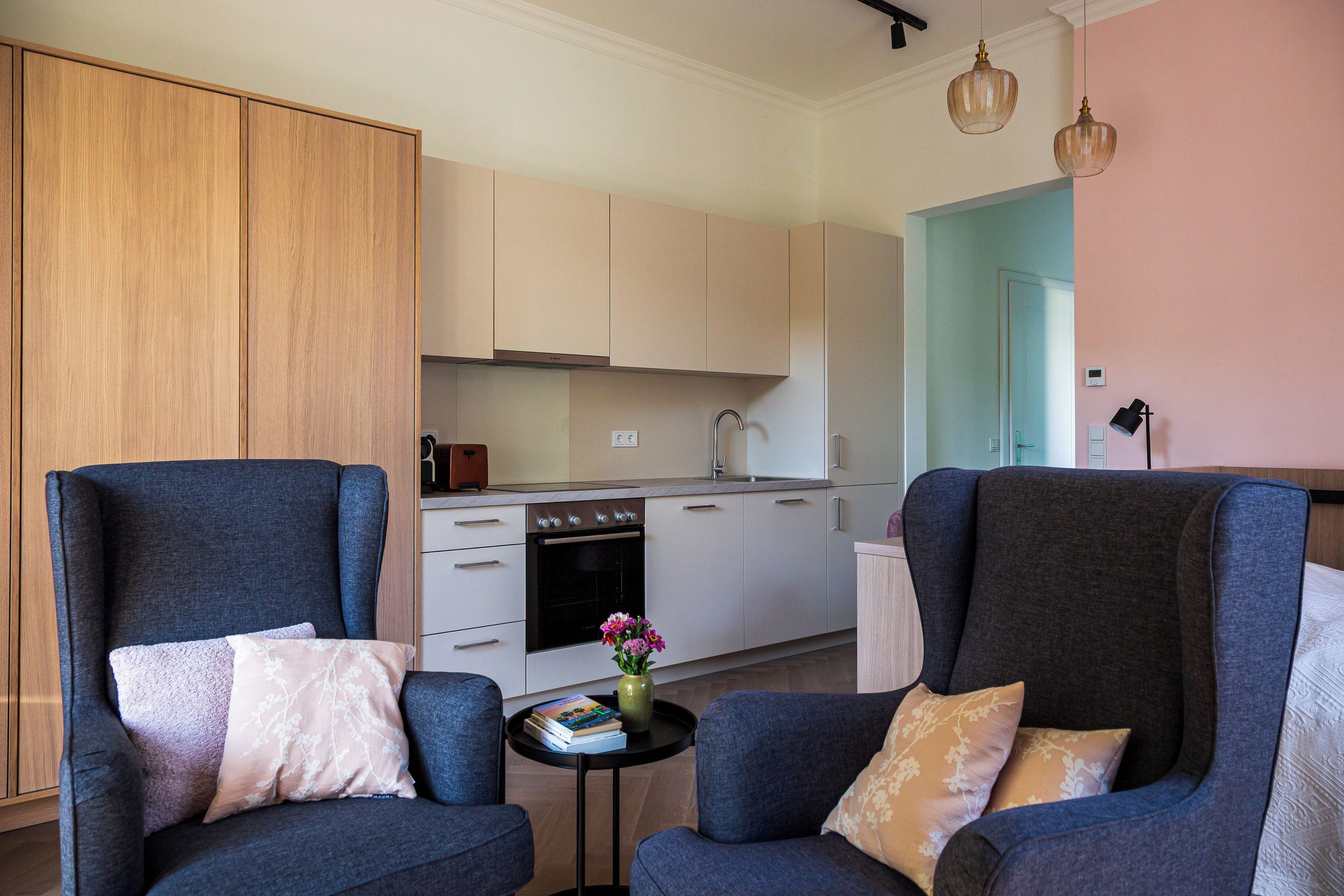 A modern living room with two armchairs, a small side table, and a kitchen in the background.